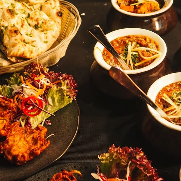 Rich Indian feast featuring naan bread, crispy pakoras, and multiple bowls of curry.